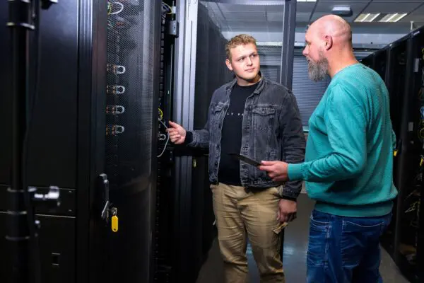 Two colleagues working together in a server room.