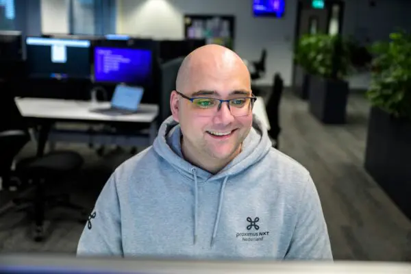 male IT expert sitting behind a desk smiling and working